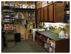 (Image: Wet Counter with Cupboards Above.
         Brushes hang on the Pegboard Wall Behind the Work Surface)